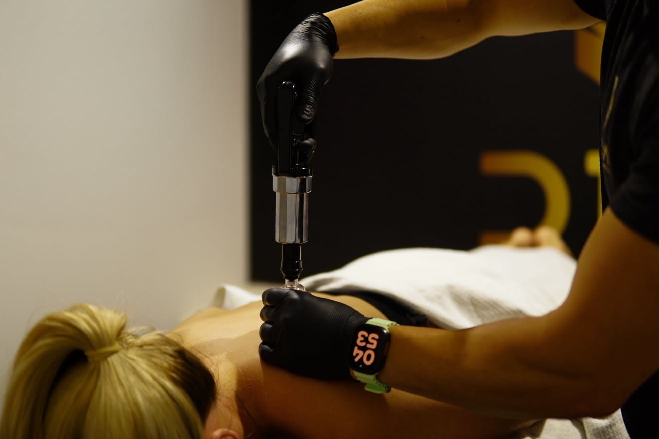 Percussion therapy applied to the upper back during treatment