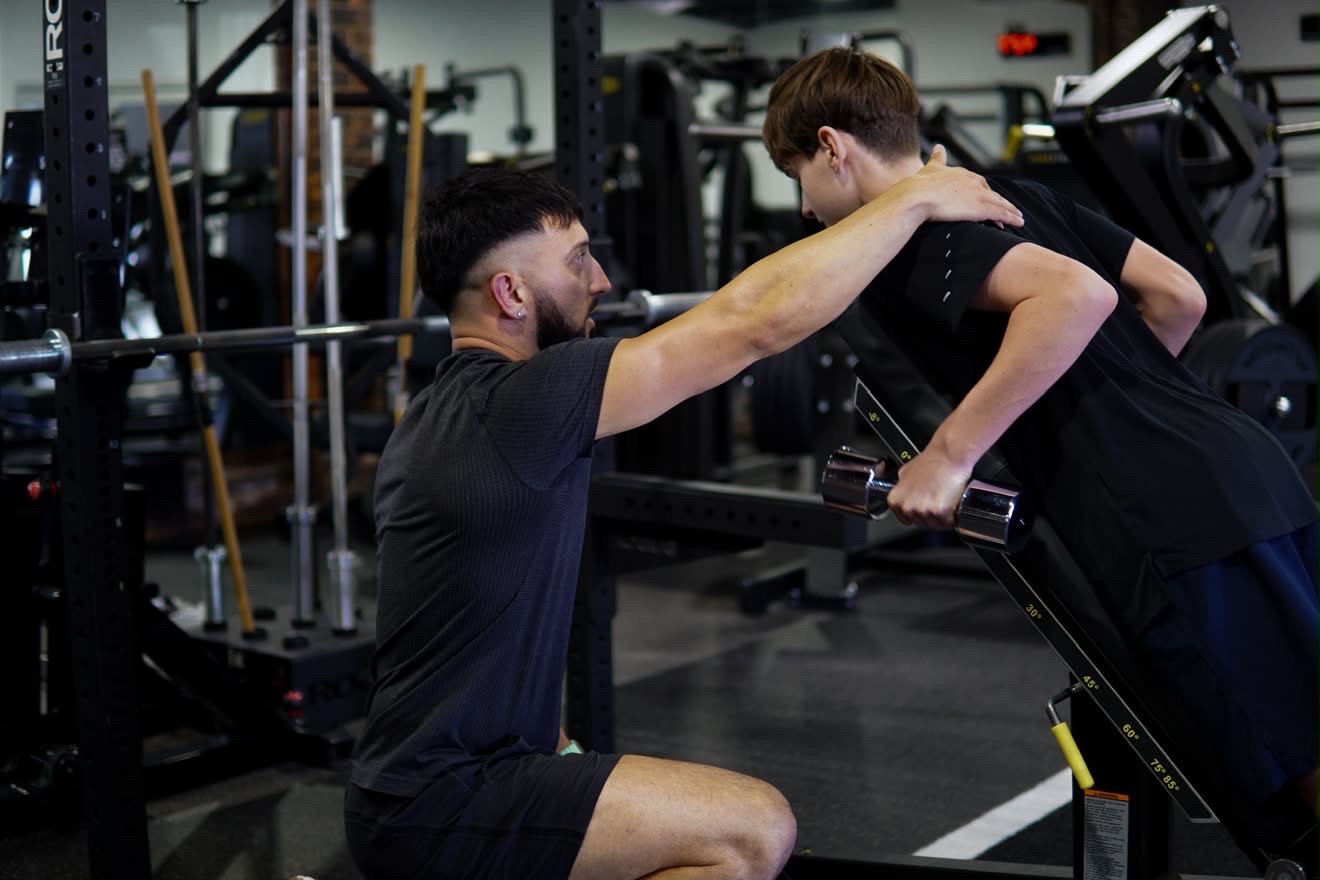 Coach guiding a barbell session at the rack inside D1M1 Fitness